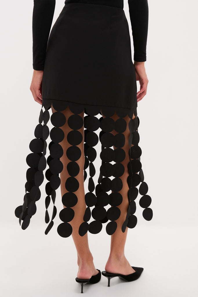 Black Multi Circle Mercedes Maxi Skirt with matte black disc fringe, styled effortlessly with minimalist black mules, exuding classic, high-end fun and graphic movement.