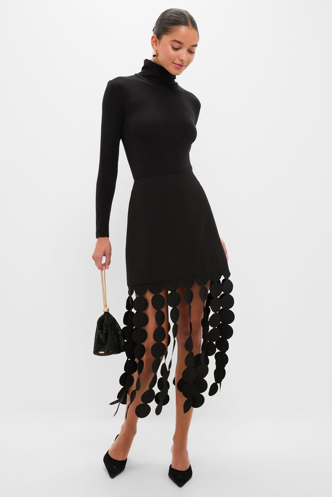 Model showcasing the Black Multi Circle Mercedes Maxi Skirt, featuring a fringe layer with circular cutouts for an effortless, high-end look. Paired with a classic turtleneck and chic accessories.