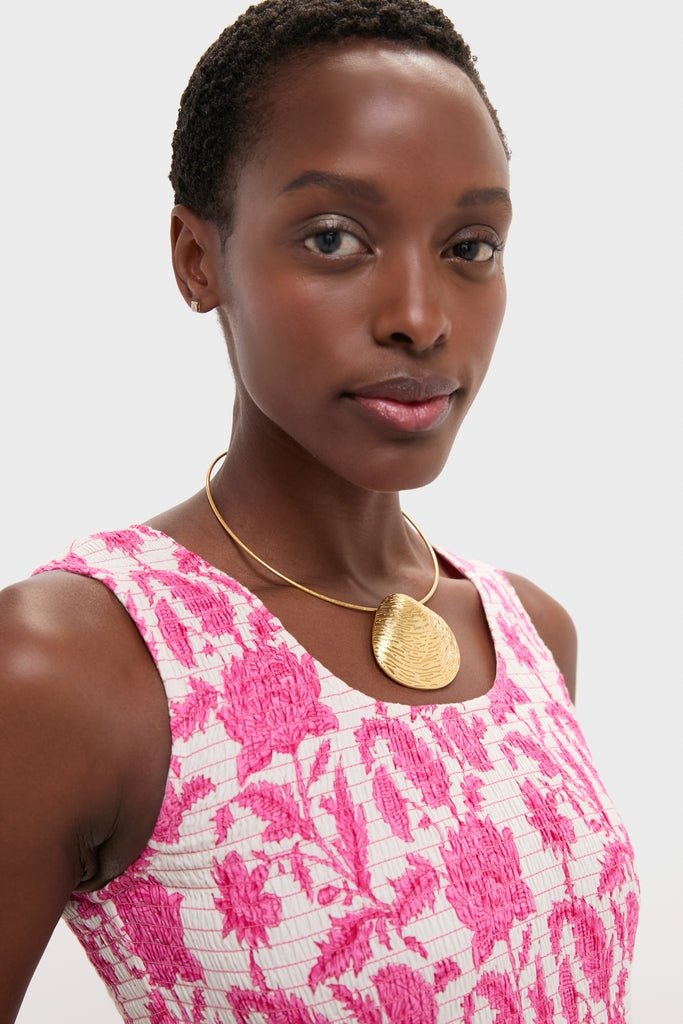 Young person wearing a sleeveless floral top and the classic Gold Clam Shell Lillian Necklace with a textured teardrop pendant, showcasing effortless, high-end style.