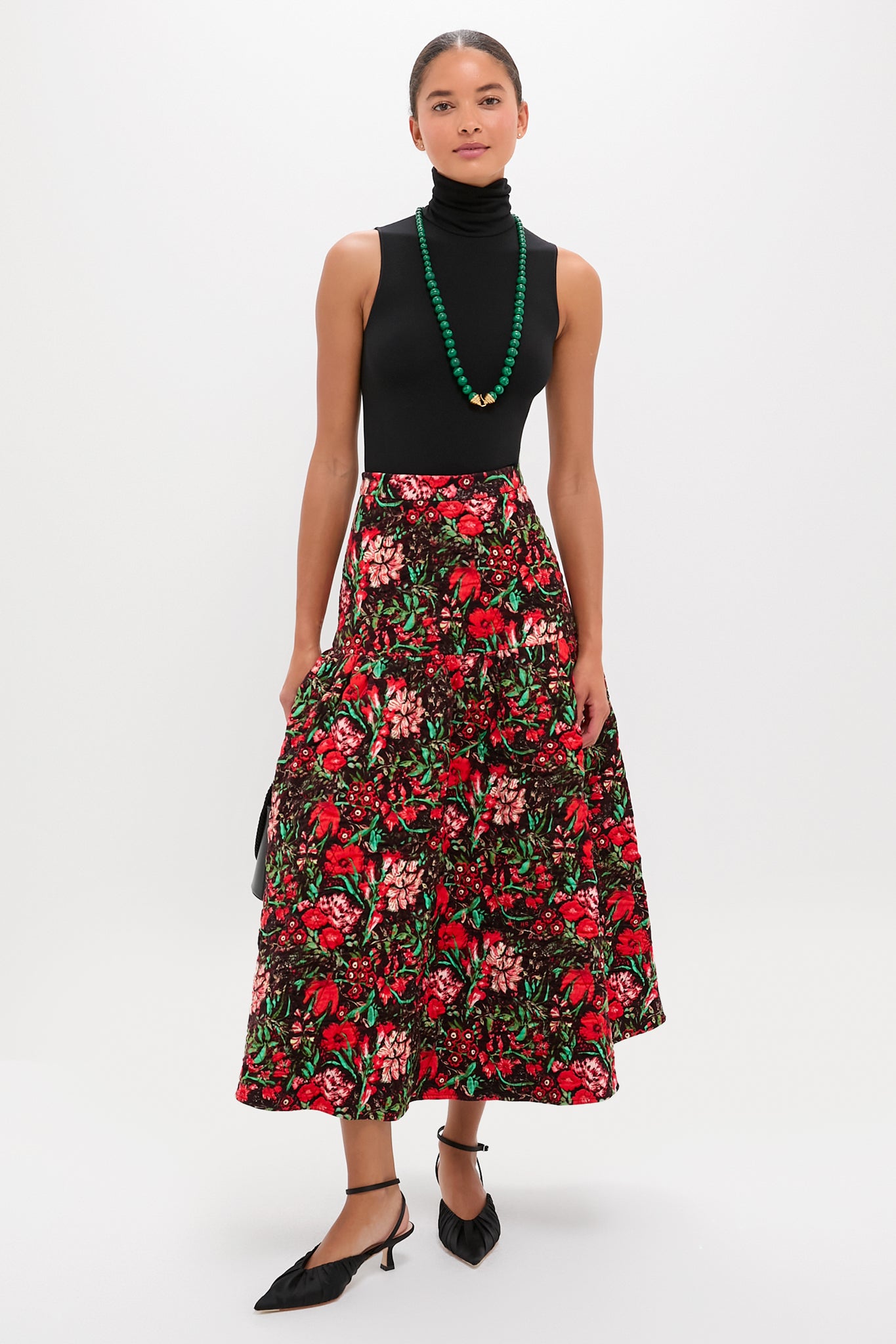 Woman wearing the Malachite Double Strand Celine Necklace, styled effortlessly with a classic black bodysuit and floral skirt, capturing a fun, high-end, and confident look.