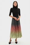 Woman models the classic Ombre Sequin Bleeker Maxi Skirt, showcasing an effortless, high-end look with a pleated ombré design, paired with a fitted black turtleneck.
