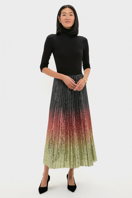 Woman models the classic Ombre Sequin Bleeker Maxi Skirt, showcasing an effortless, high-end look with a pleated ombré design, paired with a fitted black turtleneck.
