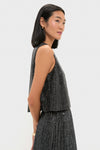 Woman modeling the Charcoal Sequin Bowery Top, a classic, sleeveless, boxy-cut design paired with a matching pleated skirt, embodying an effortless, high-end, fun style.
