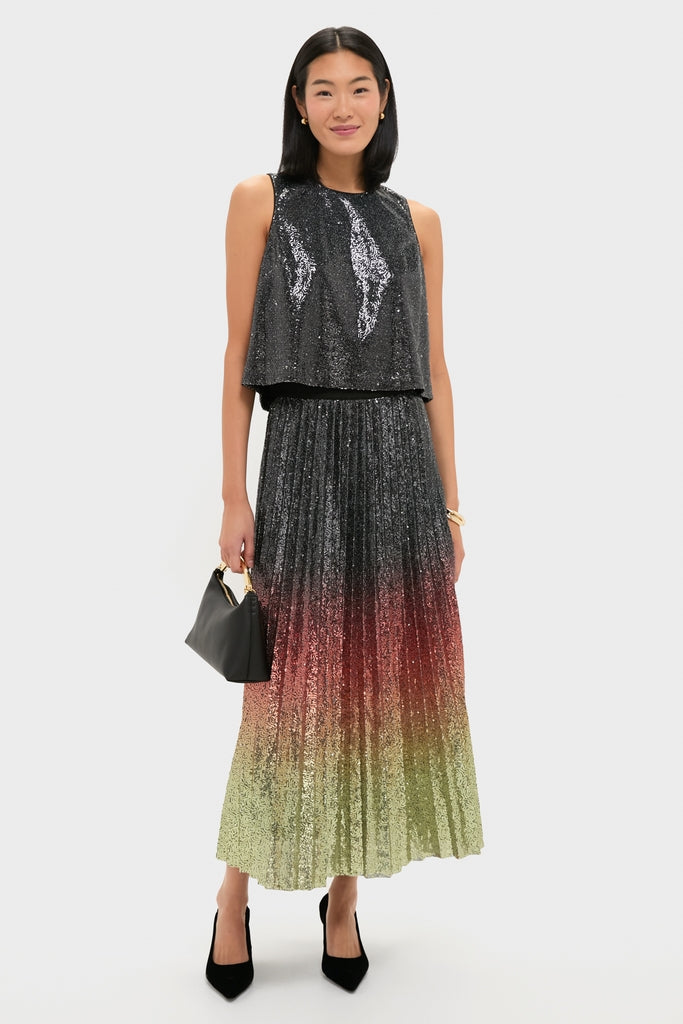 Woman models the Charcoal Sequin Bowery Top—an effortlessly chic, sleeveless, loose-fitting black sequin tank—paired with a high-end pleated maxi skirt and accessories.