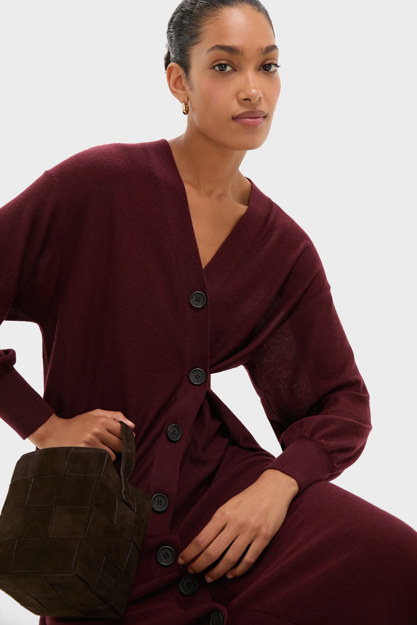 Model wearing the classic Mulberry Drippy Cardi Dress, an effortless and fun knit maxi with asymmetrical shape, holding a high-end woven-leather tote.
