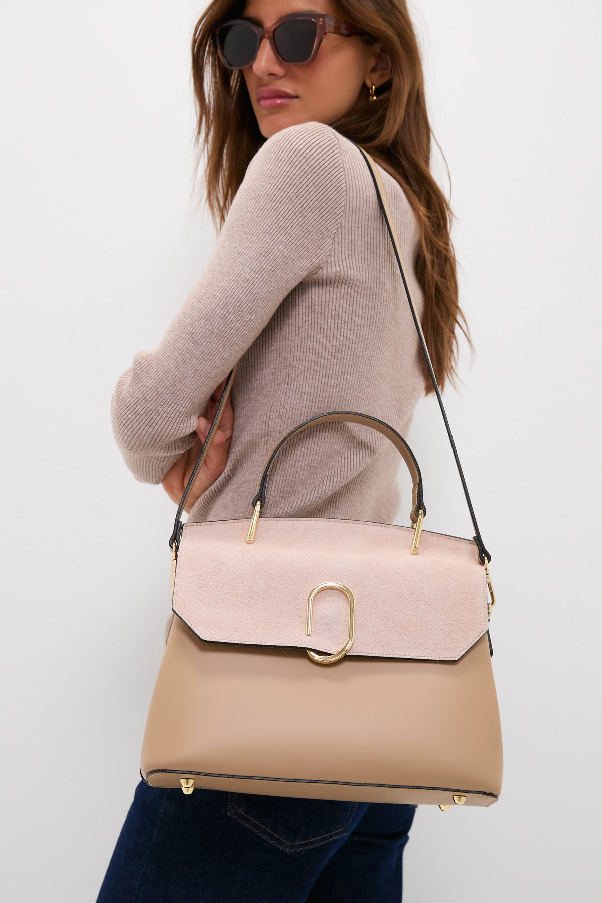 The woman models the classic Nude Thais Satchel Bag, an effortless and high-end piece with fun two-tone leather and suede, plus gold hardware.