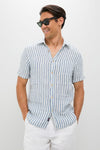 Casually dressed man in an Ivory Stripe Short Sleeve Palma Linen Shirt, exuding effortless style with classic blue-and-white stripes, embodying Tuckernuck's fun, high-end summer fashion.