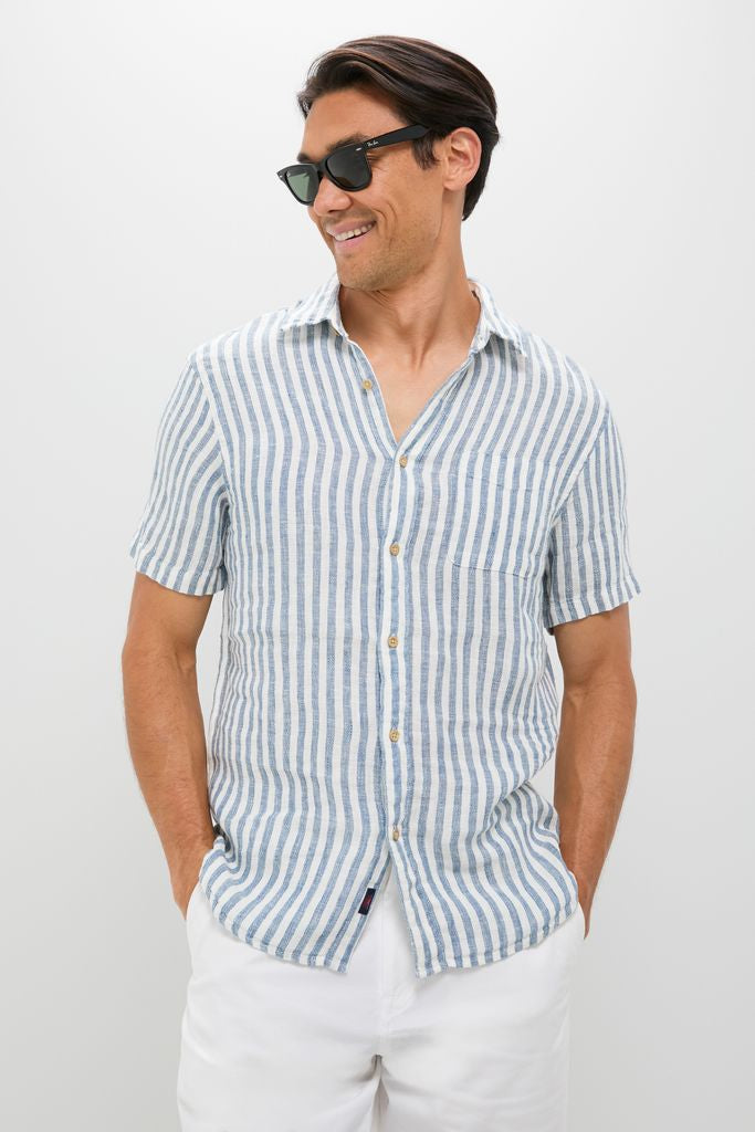 Casually dressed man in an Ivory Stripe Short Sleeve Palma Linen Shirt, exuding effortless style with classic blue-and-white stripes, embodying Tuckernuck's fun, high-end summer fashion.