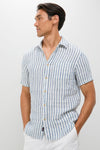 Model in an Ivory Stripe Short Sleeve Palma Linen Shirt with a classic, effortless style, featuring a button-front, chest pocket, and tailored fit, perfect for a high-end, fun summer look.