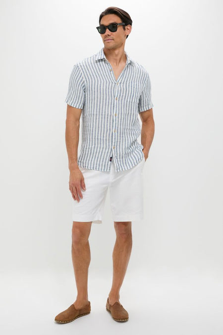 Man models the classic, effortless Ivory Stripe Short Sleeve Palma Linen Shirt, paired with white shorts and espadrilles, embodying a high-end, fun, and casual summer style.