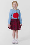 Young girl in a classic, light-blue Apple Constance Sweater with gathered puff shoulders, paired with a fun checkered skirt and high-end white sneakers. Effortlessly cool and confident look.