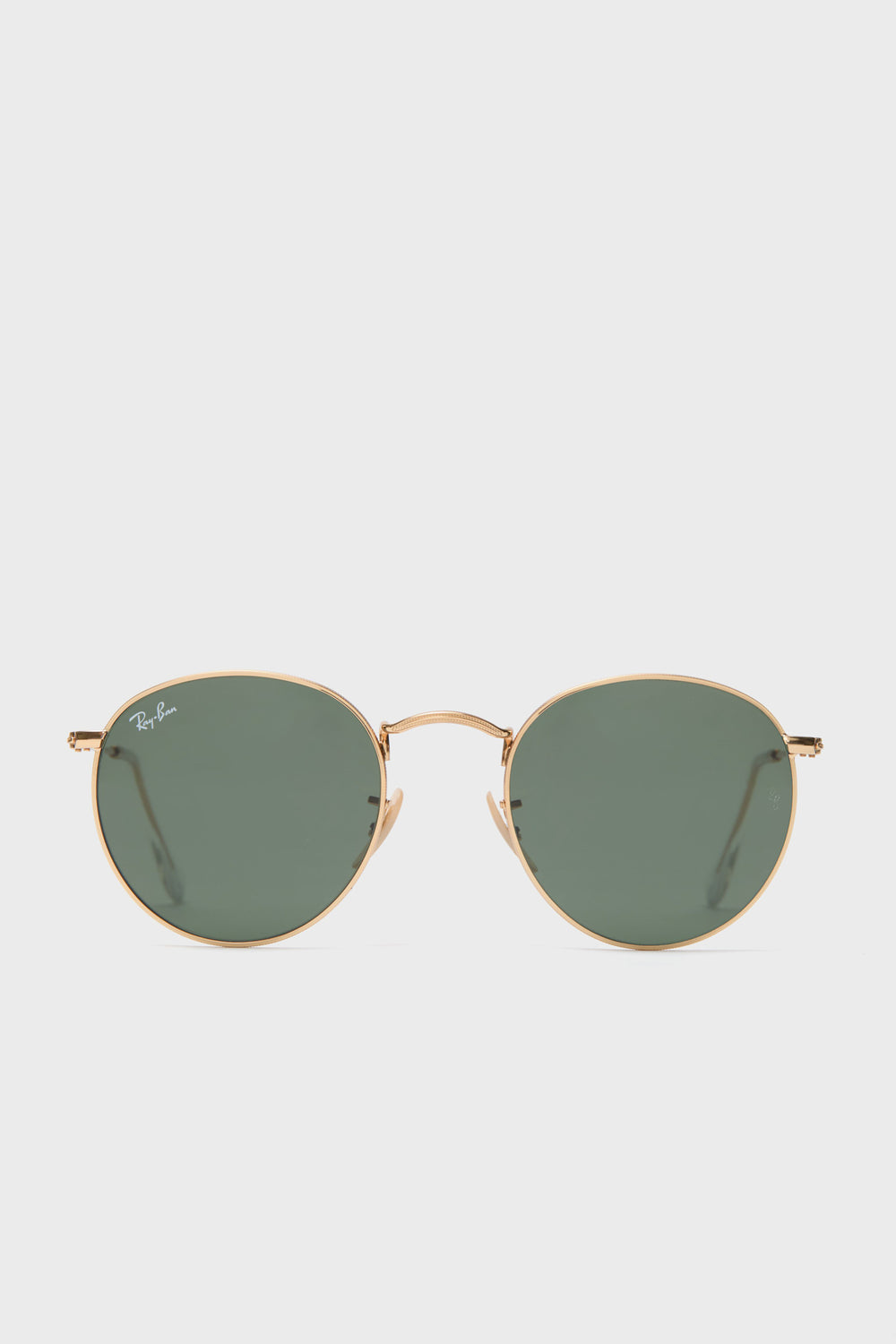 A pair of Ray-Ban round sunglasses with a gold frame and green-tinted lenses is displayed.