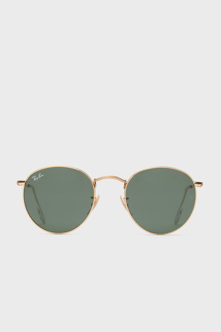 A pair of Ray-Ban round sunglasses with a gold frame and green-tinted lenses is displayed.