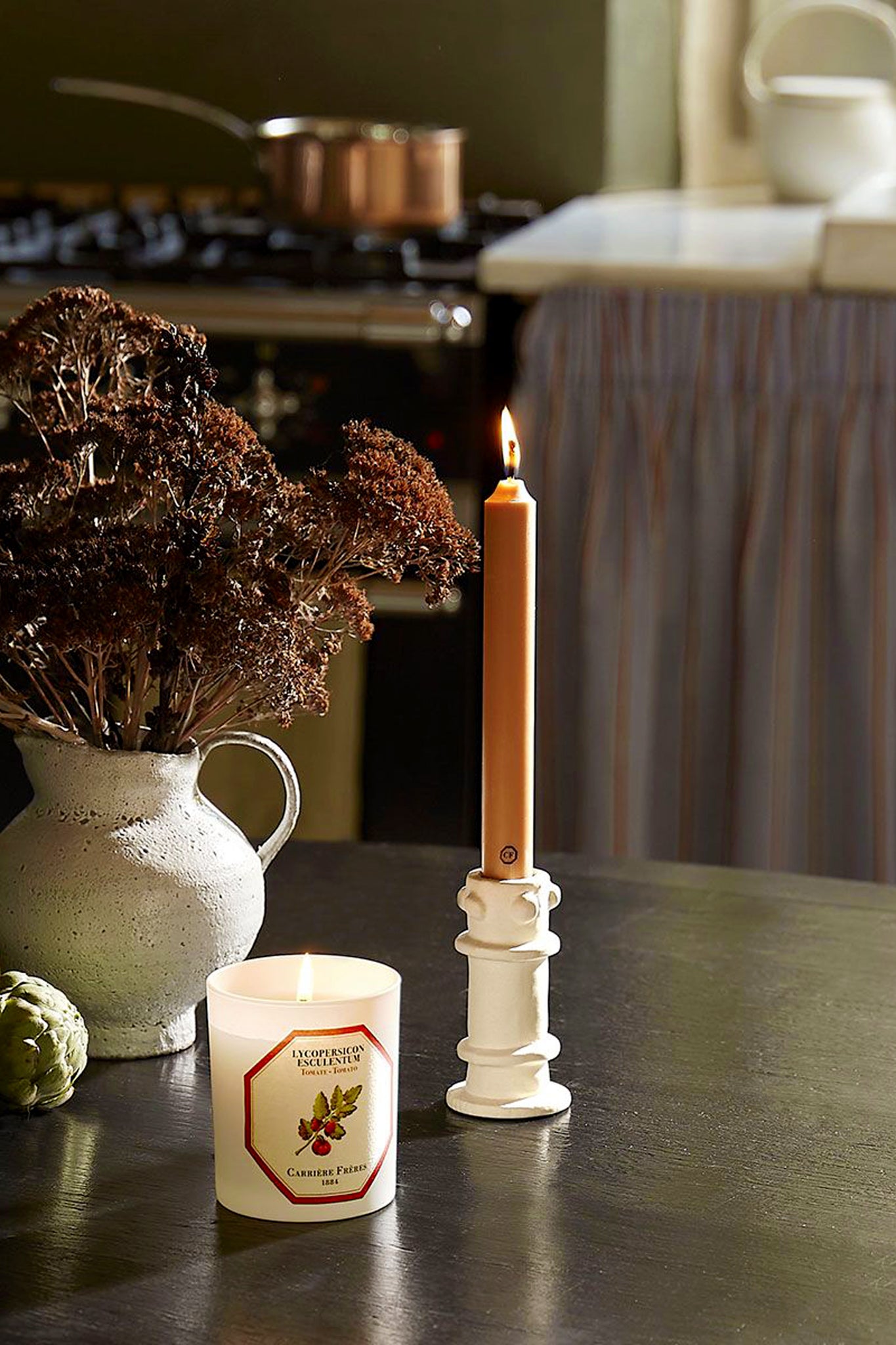 Tomato Candle in a classic frosted jar, paired with a sculptural taper candle and rustic décor, embodies effortless elegance and fun, evoking high-end botanical luxury.