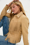 Woman wearing Tan Deerskin Fringe Jacket with a classic, effortless Western style; features swinging fringe trim and a shrunken fit, paired with blue denim jeans.