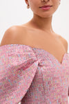 Woman wearing the Pink Multi Jacquard Off-the-Shoulder Kara Midi Dress, featuring classic puff sleeves and a gentle sweetheart neckline, paired with small drop earrings for an effortless, high-end look.