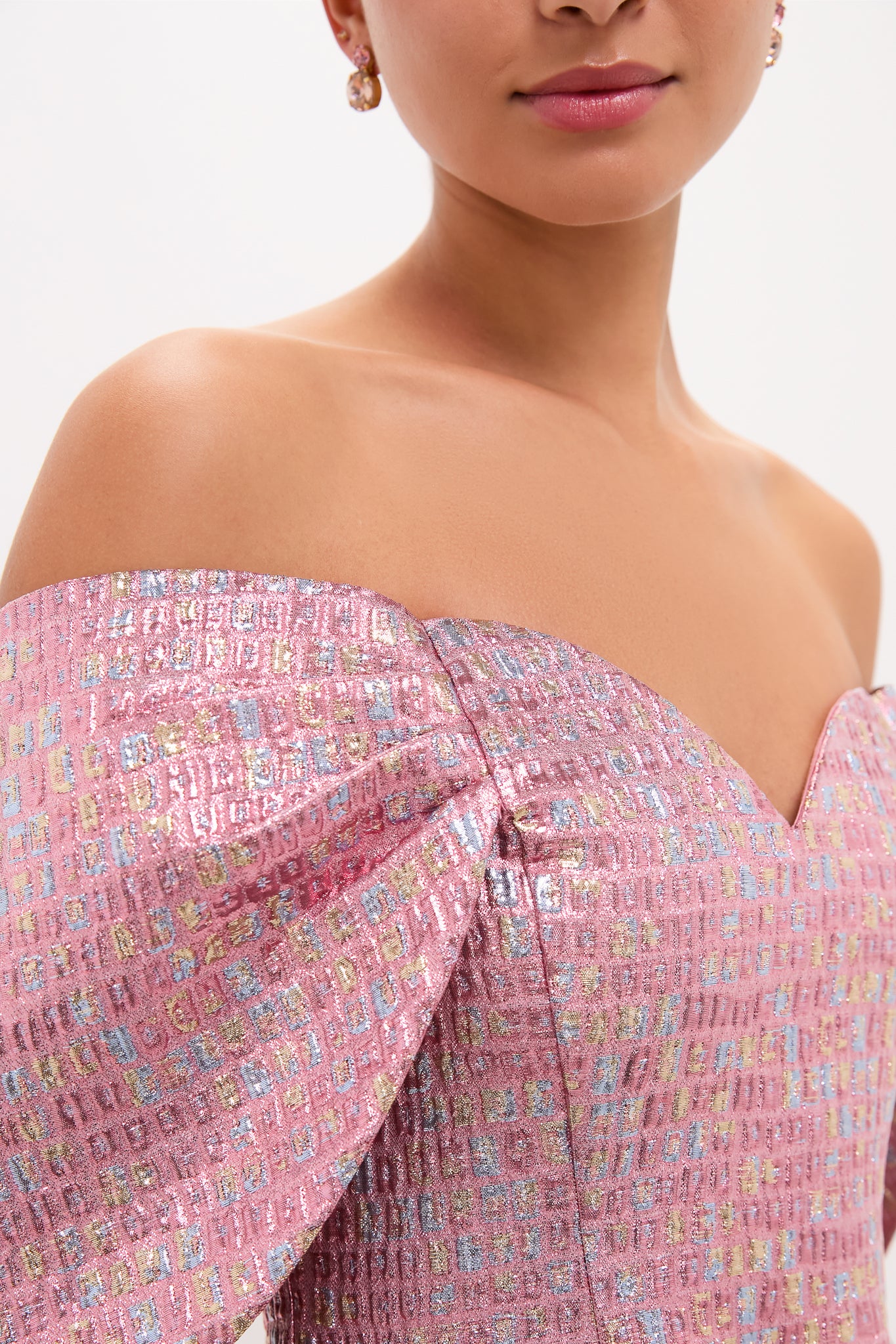 Woman wearing the Pink Multi Jacquard Off-the-Shoulder Kara Midi Dress, featuring classic puff sleeves and a gentle sweetheart neckline, paired with small drop earrings for an effortless, high-end look.