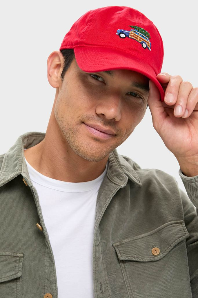 Young man tipping the Exclusive Needlepoint Christmas Dad Wagon Hat, featuring a classic hand-stitched car and tree detail, embodying effortless style and fun high-end craftsmanship.