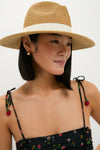 Model wearing the Exclusive Ivory Wide Brim Sun Hat by Toucan Hats. This classic, effortless straw fedora with white ribbon detail is perfect for a high-end, fun look.