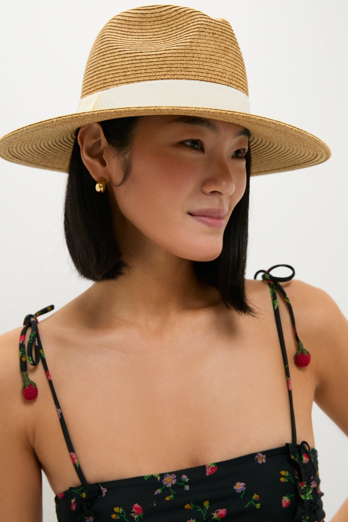 Model wearing the Exclusive Ivory Wide Brim Sun Hat by Toucan Hats. This classic, effortless straw fedora with white ribbon detail is perfect for a high-end, fun look.