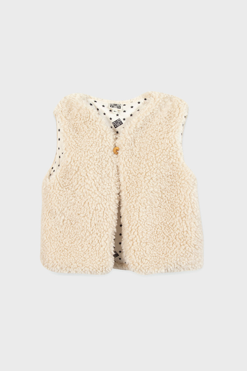 A sleeveless, cream-colored teddy vest by Bonton with a single front button and white lining adorned with small black stars—an ideal way to add Parisian chic to children’s outfits.