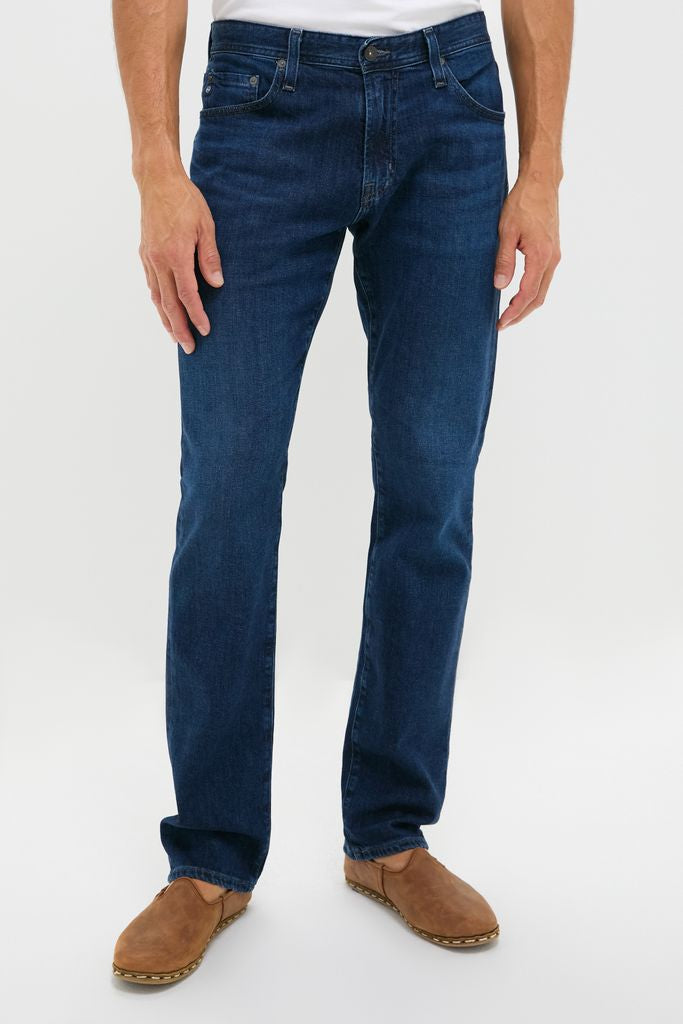 Classic dark-blue denim jeans, The Graduate in Crusade Wash Denim, paired with brown slip-on shoes, exude an effortless, high-end style perfect for fun, versatile outfits.