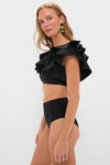 Model in Black Mila Two Piece swimsuit featuring a classic single-shoulder ruffled top and high-waisted bottoms, embodying effortless, high-end style and fun beach-ready elegance.