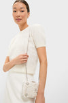 Young woman in a classic ivory ensemble holds the high-end Ivory Beth Encrusted Clutch, featuring crocheted flowers and silver crystals, radiating effortless elegance and fun.
