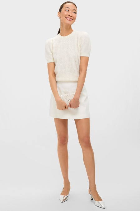 Ivory Beth Encrusted Clutch with crocheted flowers and silver crystals, held by a woman in a chic, classic ensemble. Effortless, fun, and high-end accessory for special occasions.