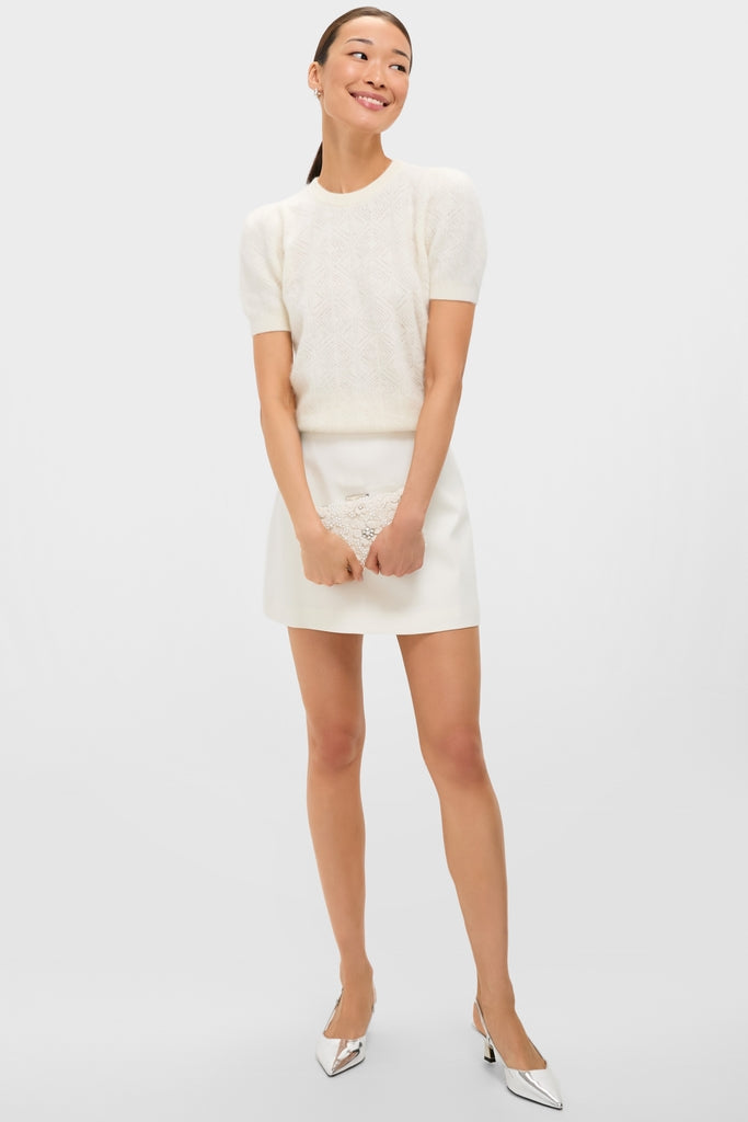 Ivory Beth Encrusted Clutch with crocheted flowers and silver crystals, held by a woman in a chic, classic ensemble. Effortless, fun, and high-end accessory for special occasions.