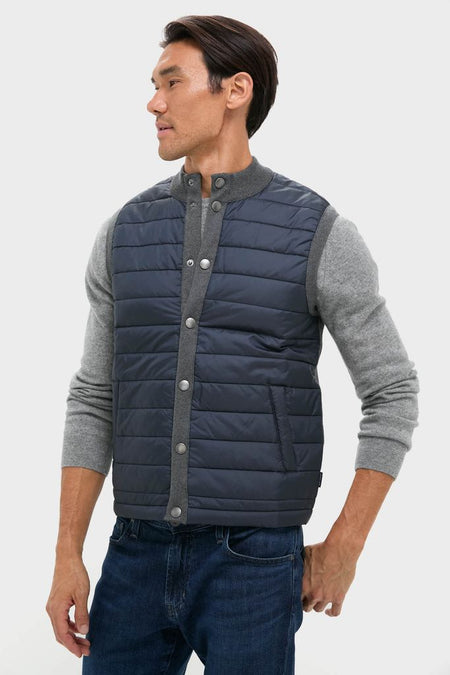 Male model wearing the classic Mid Gray Essential Gilet, a high-end, effortless vest with a quilted front and snap closure, styled over a grey pullover.