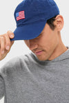 Person wearing the Navy American Flag Needlepoint Hat, tipping its brim. The classic, high-end cap features a hand-stitched flag motif, offering an effortless, fun style.