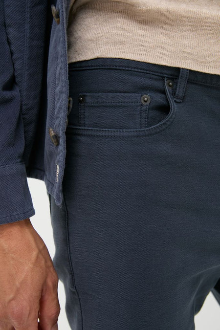 Person wearing classic Navy Stretch Terry 5 Pocket pants, embodying an effortless, high-end style under a beige sweater and navy jacket, capturing a fun, transitional fall look.