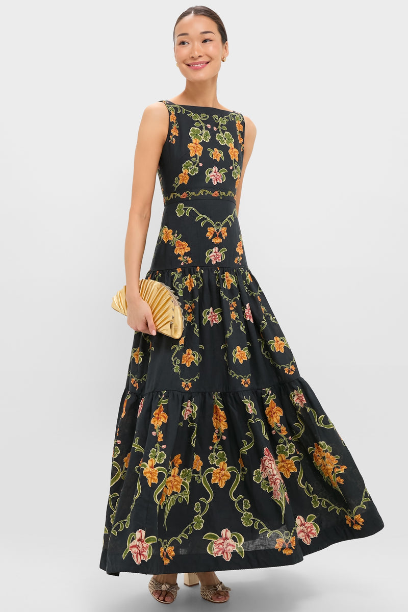 Woman elegantly showcases the Gold Nala Mini Clutch, a classic, high-end pleated bag. Effortlessly pairs with her floral maxi dress and open-toe heels for a fun, stylish look.