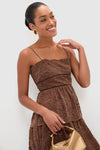 Smiling woman models the Sepia Lace Leina Midi Dress, showcasing its classic, effortless tiered skirt and fitted bodice. Paired with high-end gold accessories for a fun, elegant look.