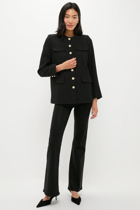 A woman stands against a white background wearing a black tweed blazer with gold buttons, black pants, and black heels by Pomander Place.