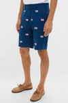 Model wearing classic Navy American Flag Embroidered Stretch Twill Cisco Shorts with belt loops, button closure, and tan boat shoes, exuding effortless, fun, high-end coastal style.