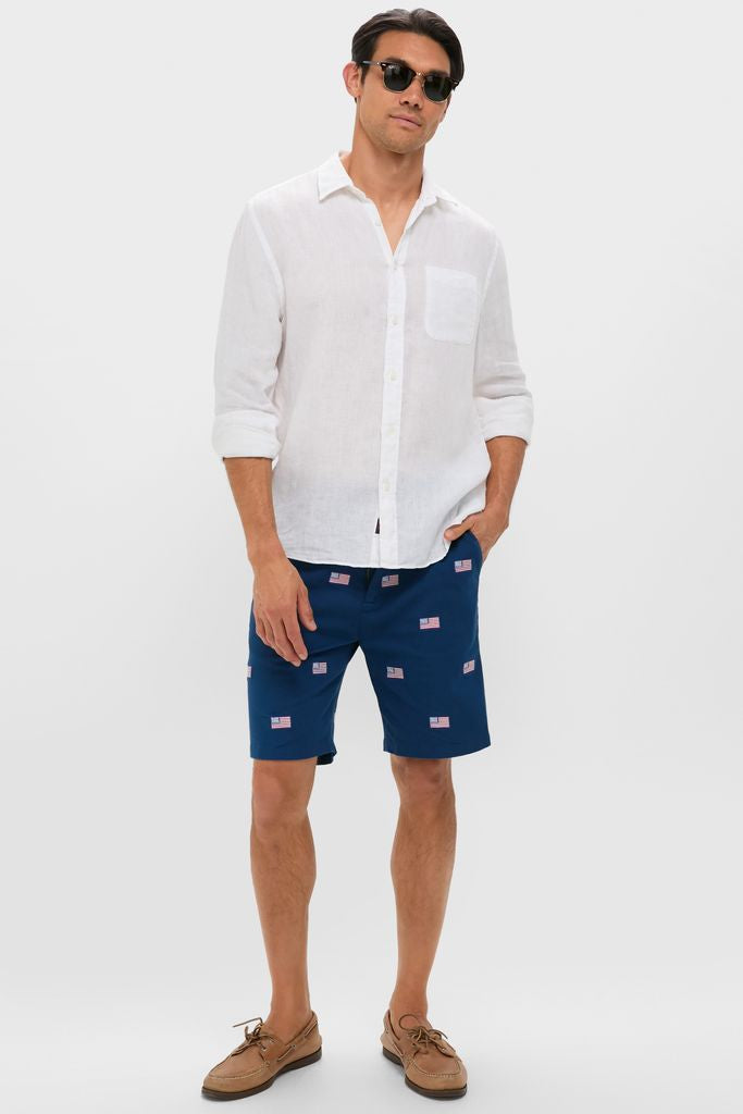 Male model wearing classic Navy American Flag Embroidered Stretch Twill Cisco Shorts, rolled sleeve white linen shirt, and boat shoes, exuding effortless, high-end, and fun summer style.