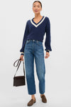 Woman in a classic Washed Navy Ashe Sweater with contrast V-neckline, paired with jeans and loafers, exuding an effortless, high-end style.