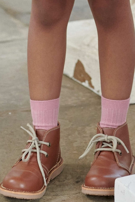 Child wearing classic Dark Tan Leather Kids Desert Boots with light pink ribbed socks, showcasing effortless style and high-end Spanish craftsmanship for fun everyday adventures.
