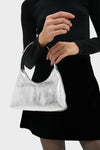 A person holds the classic Silver Mini Candy Bag, featuring an effortless crescent shape and high-end metallic finish, perfect for fun, stylish outings.