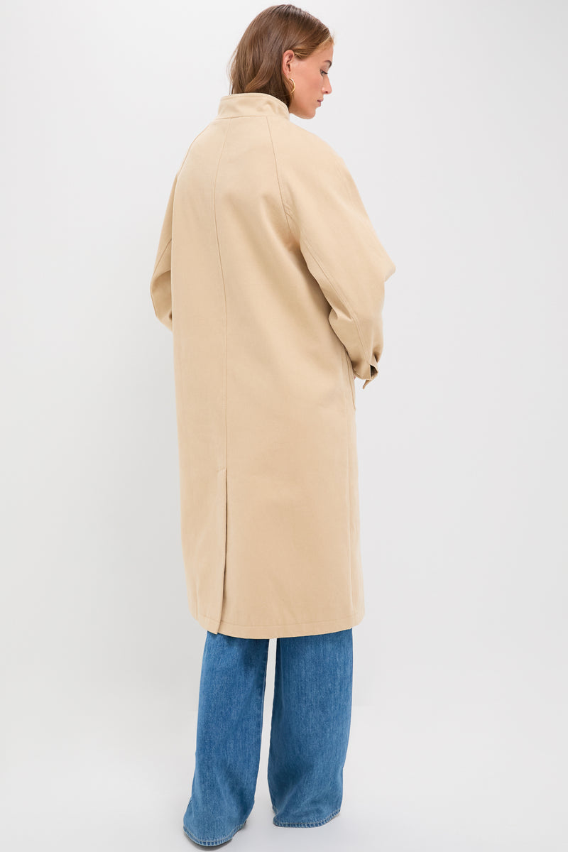Person in a classic, beige Oakley Coat over jeans, embodying an effortless, high-end look with fun, modern details like button cuffs and flap pockets.