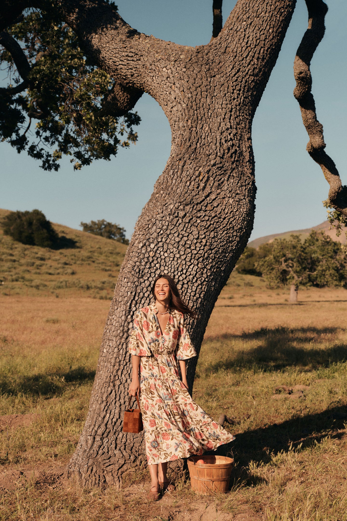 Woman standing in front of a tree in a floral maxi dress. 