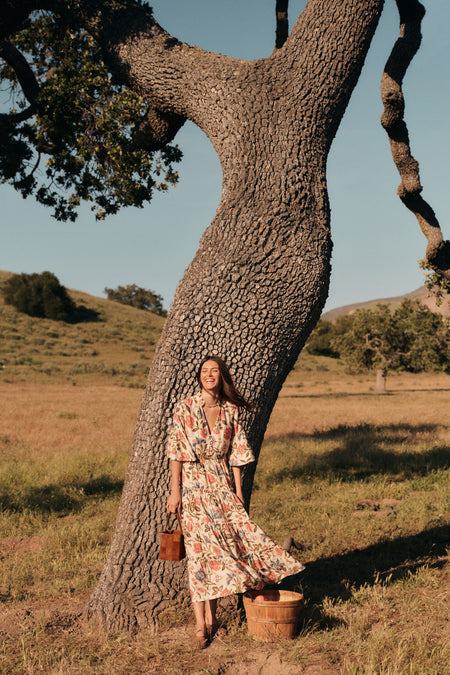 Woman standing in front of a tree in a floral maxi dress. 