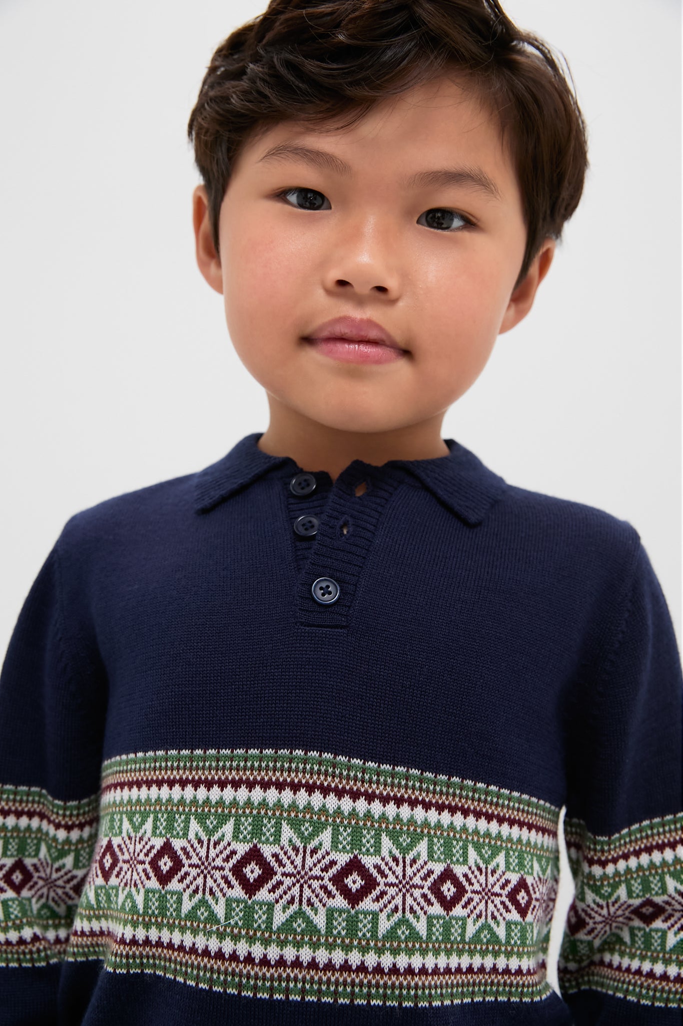 Child wearing the Fairisle Collar Sweater, a classic navy knit with a Fair Isle design. Effortless style for fun occasions, reflecting Tuckernuck's high-end, cool vibe.