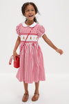 Young girl in a classic Candy Cane Stripe Smocked Dress with gingerbread embroidery, exuding an effortless, fun, and high-end holiday charm.