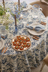 Chambray Nell Highball glasses with blue rims, elegantly set on a refined table with fritters and floral decor, embody classic, effortless, and fun dining sophistication.