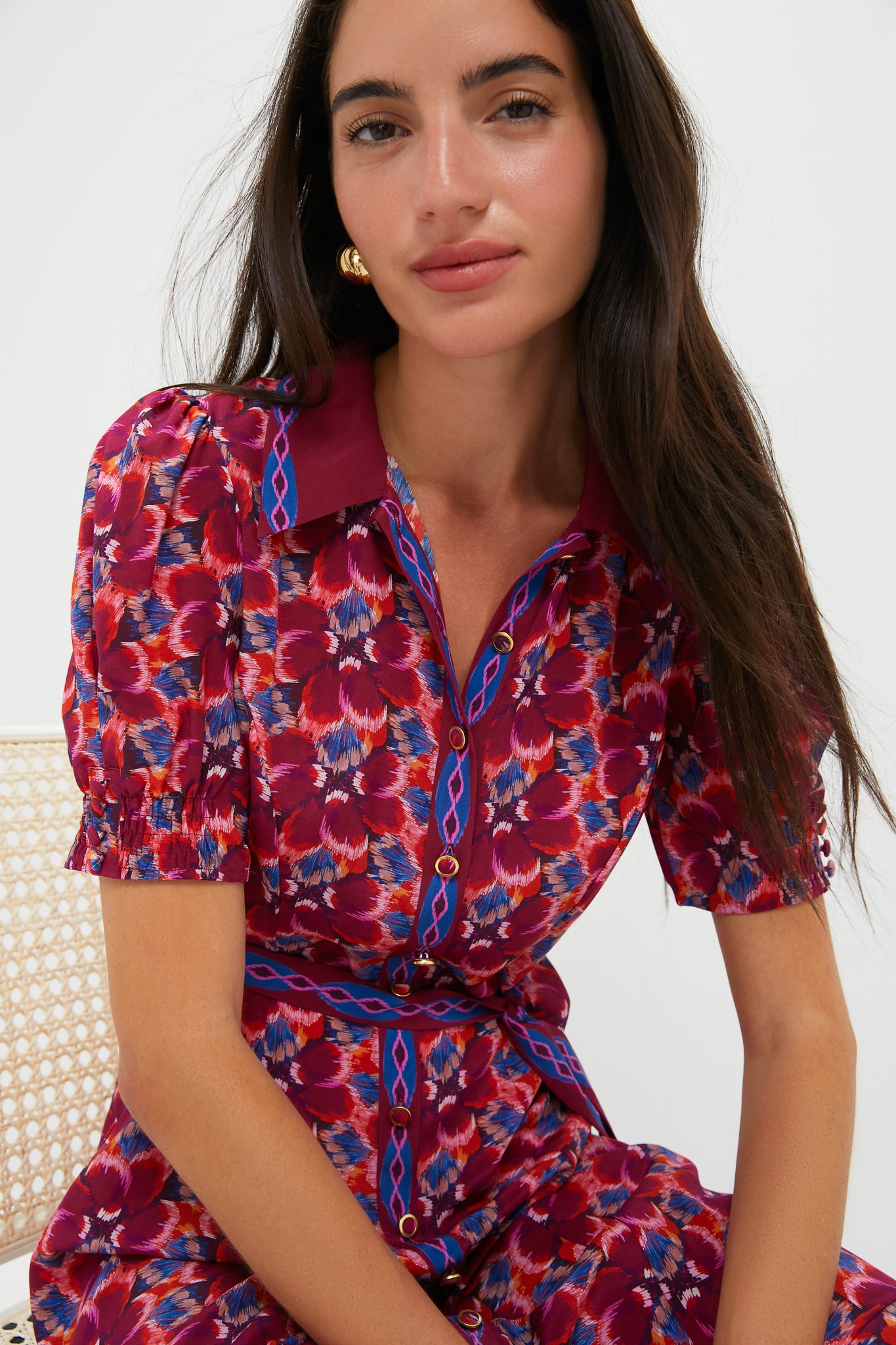 Young woman seated on a chair, wearing the classic Quail Magenta Vanessa-D Midi Dress with an abstract floral pattern, exuding effortless, high-end style.