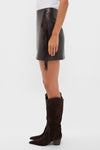 Model wearing the classic Coffee Faux Leather Fringe Paddock Mini Skirt with fringe detail, paired with matching knee-high suede boots for an effortlessly chic, high-end look.