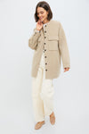 Woman wearing the Beige Chine Florian Coat, a classic, oversized shirt-jacket with chest flap pockets. Paired with cream trousers and tan ballet flats, embodying effortless, high-end style.